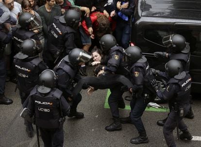 Agents antiavalots expulsen del perímetre de seguretat una jove davant del col·legi Ramon Llull de Barcelona.