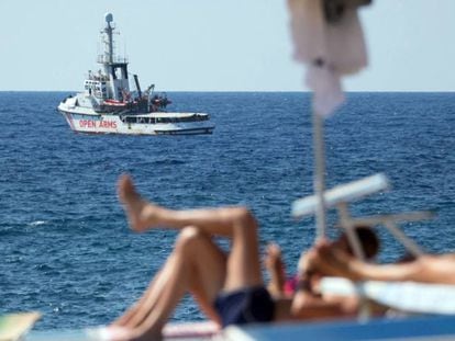 El vaixell de rescat 'Open Arms' davant les costes de Lampedusa (Itàlia) mentre uns turistes prenen el sol a l'illa.