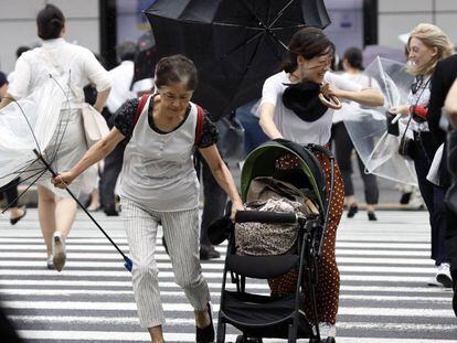 Unos peatones luchan contra los fuertes vientos y la lluvia hoy en Tokio.