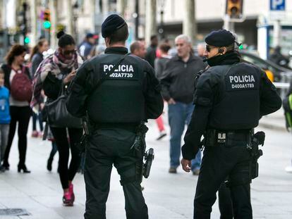 Dos agentes de los Mossos d'Esquadra patrullan por una calle