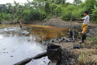 Dos operarios trabajan en las tareas de limpieza del vertido de Chevron hace tres décadas en Orellana, la Amazonia ecuatoriana.