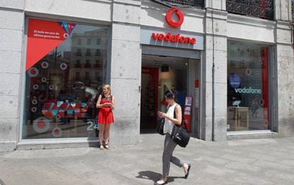 Usuaria de m&oacute;vil frente a una tienda Vodafone