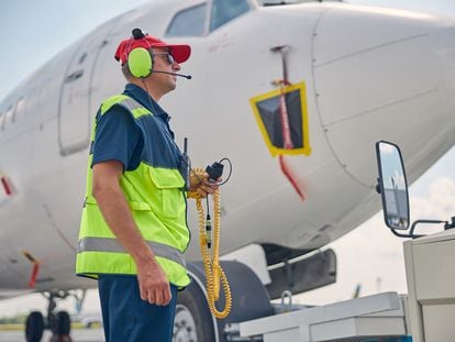 Un trabajador aeroportuario con auriculares para proteger sus oídos del ruido de los aviones.