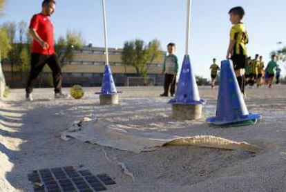 Los niños entrenan cerca de los baches del campo de Orcasitas.