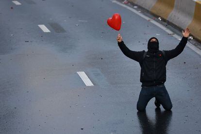 Un manifestante arrodillado sujeta un balón en forma de corazón, este domingo en Bruselas, durante una protesta por las medidas anticovid adoptadas por el Gobierno belga.