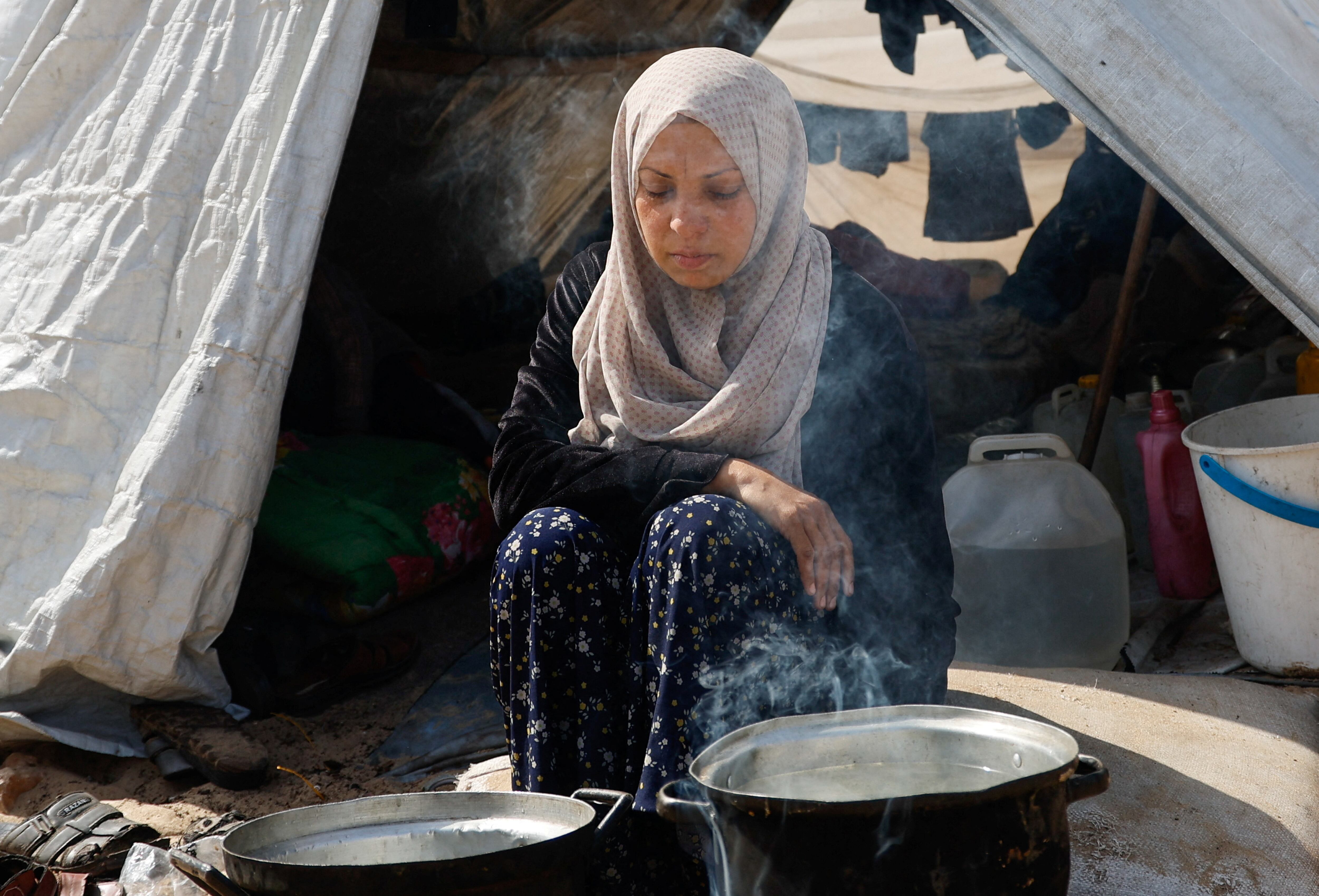 Una mujer palestina cocina en el exterior de su tienda de campaña ayer miércoles en Rafah, en el sur de Gaza.