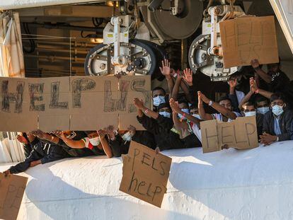 Migrantes retenidos en el muelle de Catania (Italia) muestran pancartas pidiendo ayuda, este lunes.