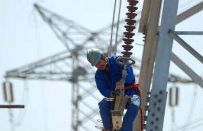 Un trabajador instala nuevas líneas de alto voltaje en una torre de electricidad. EFE/Archivo