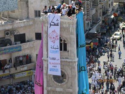 Un grupo de manifestantes anti gubernamental cuelga el cartel "Gracias Al Yazira, gracias Shaam News Network" en Hama, Siria