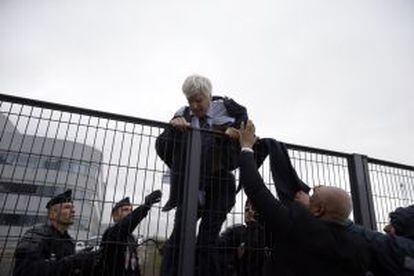 Pierre Plissonnier, con el traje y la camisa rasgados, trata de saltar una valla con ayuda de los agentes de seguridad después de que cientos de trabajadores tomasen la sede de Air France por el plan de ajuste.