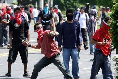 Supuestos estudiantes lanzan piedras a los policías de la Unidad del Mantenimiento del Orden hoy, miércoles 5 de julio, a las afueras de la Universidad Nacional en la capital salvadoreña.