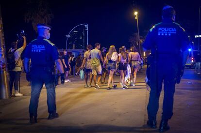 Una pareja de policías desaloja a un grupo de personas que permanecía en la calle tras el toque de queda en Barcelona.