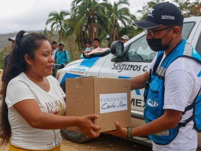 Un voluntario de la Fundación Carlos Slim entrega una caja con ayuda humanitaria a una mujer en Acapulco.
