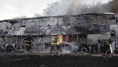 Bomberos intentan apagar las llamas de un autob&uacute;s incendiado en Jalisco. 