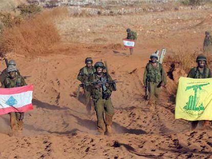 Soldados israelíes sostienen una bandera libanesa (izquierda) y otra de Hezbolá al retirarse del sur de Líbano.