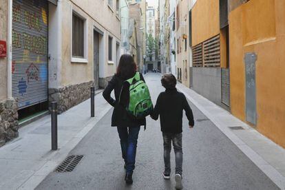 Una mare porta la motxilla del seu fill camí de l'escola.