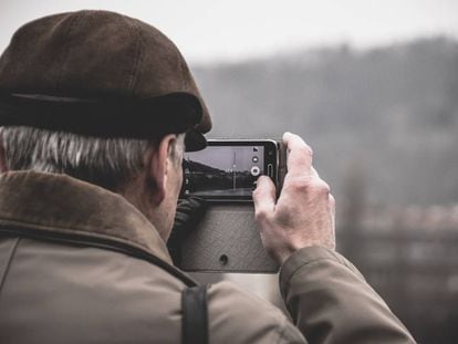 Una persona mayor de 60 años toma una foto con un móvil.