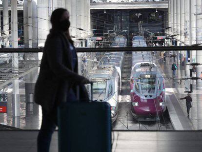 Una viajera transita por la estación Madrid Puerta de Atocha con los trenes de alta velocidad del AVE y Avlo de fondo.