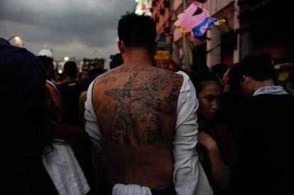 Un devoto muestra su espalda con tatuajes del Nazarenos Negro durante la procesión.