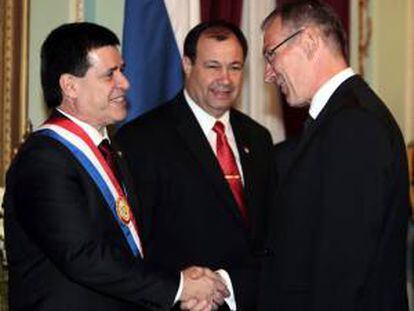 El comisario de Desarrollo de la Unión Europea, Andrés Piebalgso (d), saluda al nuevo presidente paraguayo, Horacio Cartes (i), junto a su vicepresidente, Juan Afara (c), tras la ceremonia de investidura de Cartes, en Asunción (Paraguay).