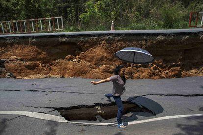 Una mujer salta una grieta en la carretera producida por el terremoto de 6 grados de magnitud que ha sufrido la ciudad de Chiang Rai, en el norte de Tailandia.