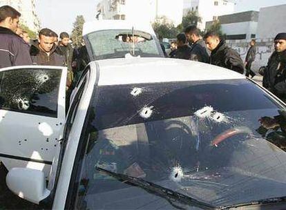 Miembros de los cuerpos de seguridad palestinos, junto al taxi tiroteado en Gaza.