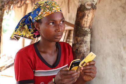 La joven Aisuto, con el teléfono móvil que le sirve para comprar comida, en el campo de refugiados de Lolo (Camerún).