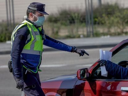 Un agente de la Policía Municipal pide a un conductor el justificante que le permite su salida de casa en un control policial de tráfico en Madrid. Foto de archivo.