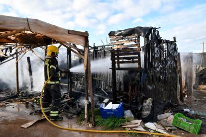 Un bombero apaga el fuego de una chabola incendiada durante el desalojo del campamento "El Walili" en Níjar (Almería). 
