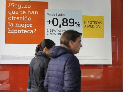 Dos personas pasan ante un cartel de promoción de una hipoteca, en Madrid.