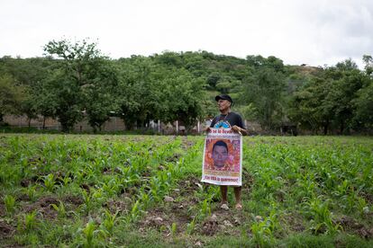 Clemente Rodríguez, padre de Christian, uno de los 43 normalistas, en su milpa con un cartel con la imagen de su hijo.