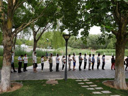 Un grupo de personas guarda cola para hacerse la prueba del coronavirus, en un parque del sur de Pekín.