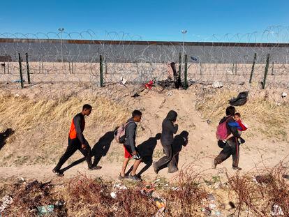 Un grupo de migrantes camina junto al muro en Río Grande, Texas.