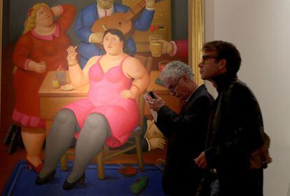 Los visitantes pasean por el Centro de Convenciones de Miami, de fondo una pintura del colombiano Fernando Botero.