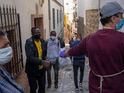 Un grupo de temporeros recoge una bolsa con alimentos, en la sede de Cáritas de Jaén.