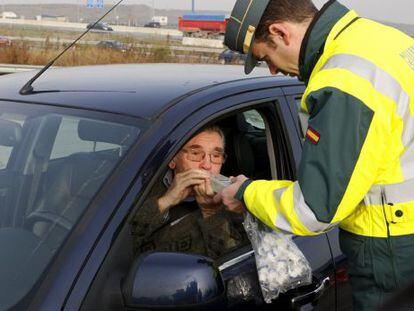 Un conductor realiza una prueba de alcoholemia en un control a instancias de un guardia civil de tráfico.