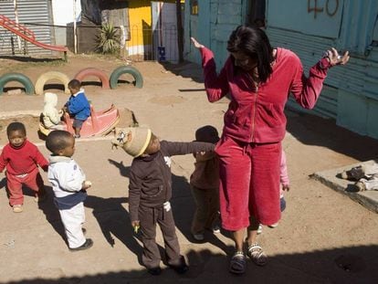 Unos niños buscan en los bolsillos de una visitante a un jardín de infancia de Soweto.