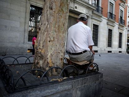 Un hombre descansa en la plaza Jacinto Benavente de Madrid, sobre un asiento improvisado con un trozo de cartón.
