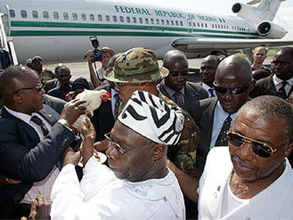 El presidente de Liberia, Taylor (derecha), y su homólogo nigeriano, Obasanjo (centro), en el aeropuerto de Monrovia.