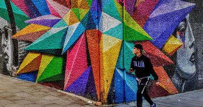 Un joven pasa junto a un grafiti en el barrio de Lavapiés.