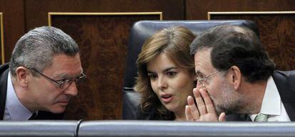 El presidente del Gobierno, Mariano Rajoy, hace confidencias a la vicepresidenta, Soraya Sáenz de Santamaría, y al ministro de Justicia, Alberto Ruiz Gallardón.