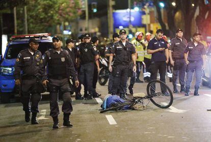 Agentes de la policía junto al cadáver de un hombre que murió cerca del estadio del Maracanã el día de la ceremonia de inauguración