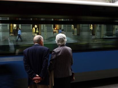 Una pareja de jubilados mira un autob&uacute;s pasar en una calle de Madrid