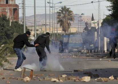 Jóvenes que intentan esquivar los gases lacrimógenos lanzados por la policía durante las protestas en Regueb, Túnez.
