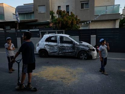Niños israelíes junto a un coche afectado por un cohete lanzado desde Gaza, el pasado martes en la localidad israelí de Sderot.