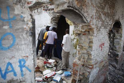 Un grupo de hombre miran a una prostituta y su cliente en medio de las ruinas de Puerto Príncipe.