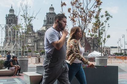 Dos personas fuman en una de las avenidas que rodean el Zócalo, en el Centro Histórico de Ciudad de México.