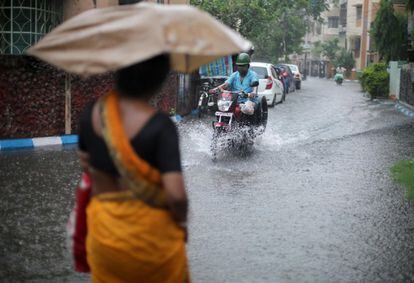 Varios ciudadanos indios circulan por una calle inundada tras las fuertes lluvias caídas en Kolkata, India.