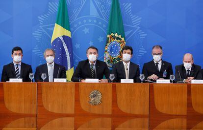 El presidente brasileño, Jair Bolsonaro (al centro), ofrece una conferencia de prensa sobre el nuevo virus que afecta al mundo en el Palacio de Planalto en Brasilia, en Brasil, acompañado de su gabinete. Todos usan mascarillas para protegerse de la pandemia.