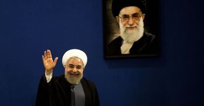 El presidente Rohani saluda junto a un retrato del ayatolá Jamenei tras una rueda de prensa en Teherán.